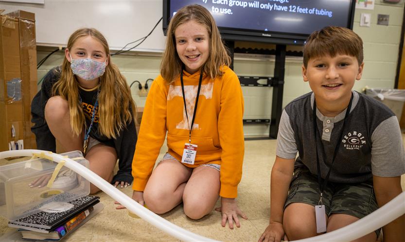 Three students work on a mini rollercoaster track